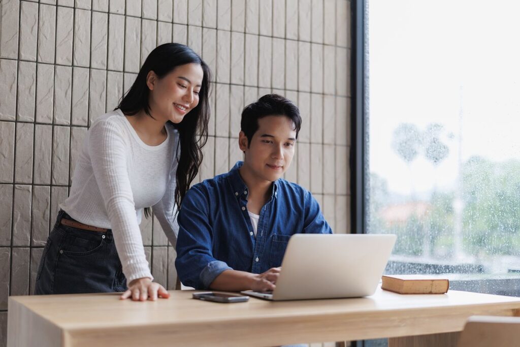 Two professionals working together on a laptop in a modern office