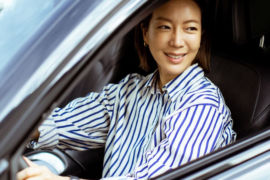 Woman in a striped shirt seated behind the steering wheel of a car in Ortigas